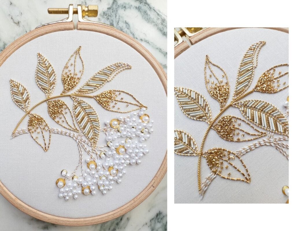 Detailaufnahme einer Stickerei mit goldenen Blättern und Perlen auf weißem Stoff.